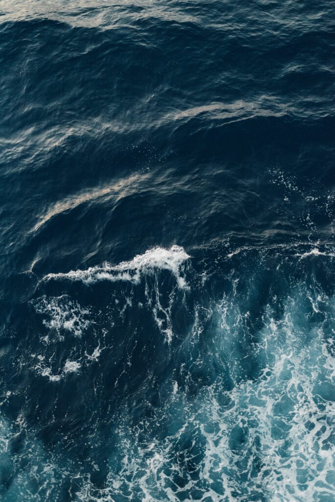 Ocean waves with deep blue hues and white crests creating a serene refreshing wallpaper background