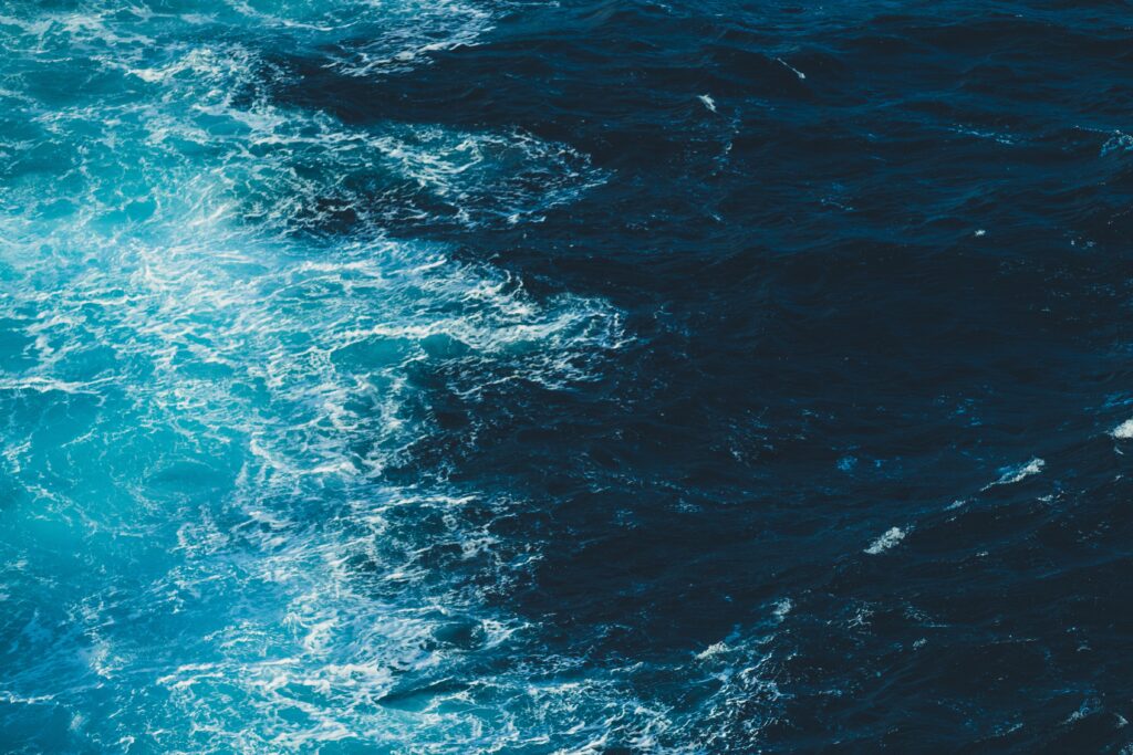 Ocean wallpaper with deep blue and turquoise waves and foamy white crests creating calm energy