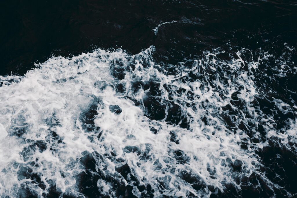 Dynamic ocean waves with swirling swash and frothy foam in deep navy and white tones wallpaper background
