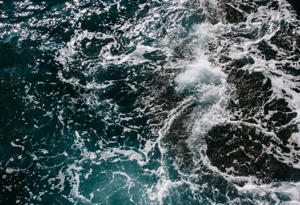 Dynamic swirling sea waves with foamy surf in deep blue and turquoise high-resolution wallpaper