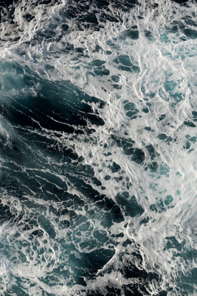 Dynamic ocean waves with swirling blue water and white foam creating a refreshing aquatic scene Wallpaper