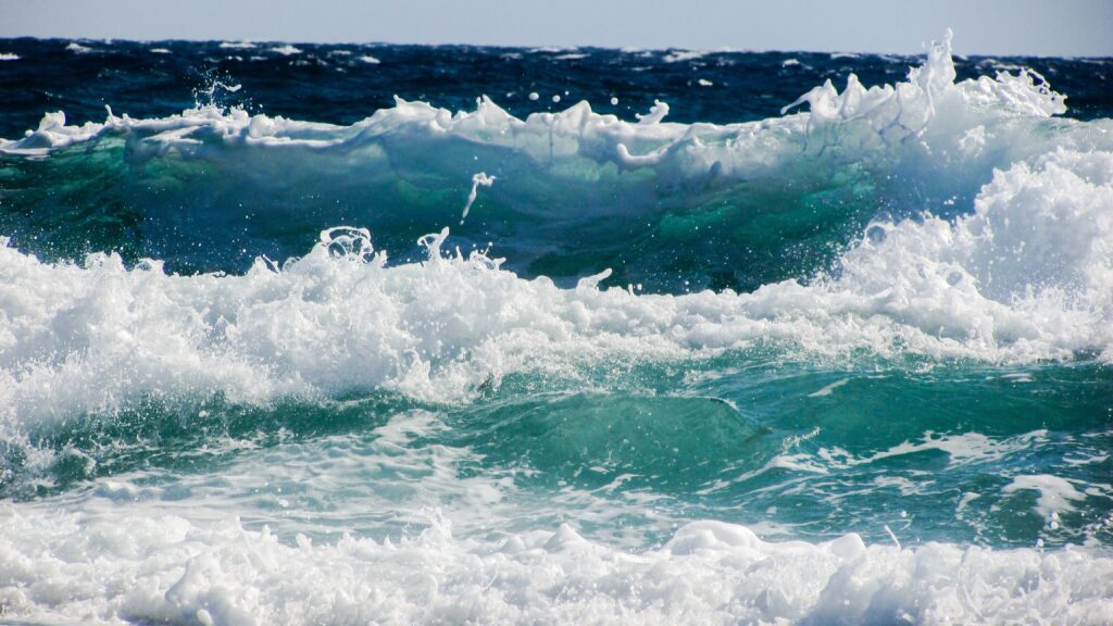 Vibrant photorealistic ocean wallpaper with powerful waves swirling foam and turquoise blue sea spray