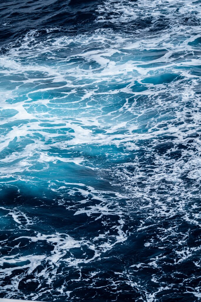 Dynamic ocean wallpaper with deep blue waves swirling white foam and vibrant turquoise tones