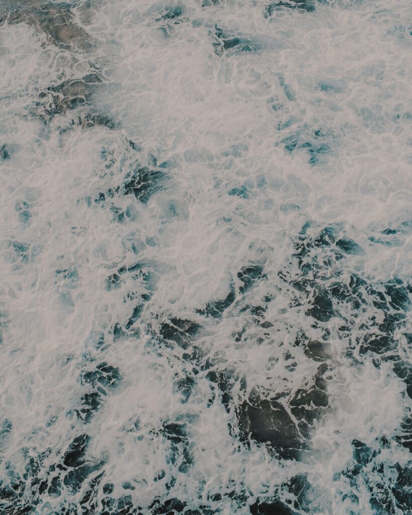 High-resolution ocean wallpaper with deep blue waves and swirling white foam crashing powerfully