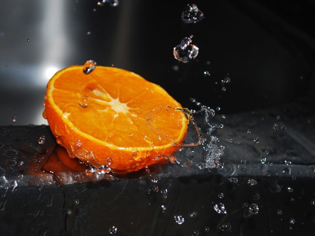 Vibrant Orange Segment Splash Close-Up Wallpaper - Refreshing Visual