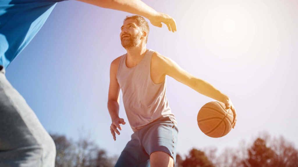 Two basketball players in intense outdoor match with sunlit court and dynamic action scene Wallpaper