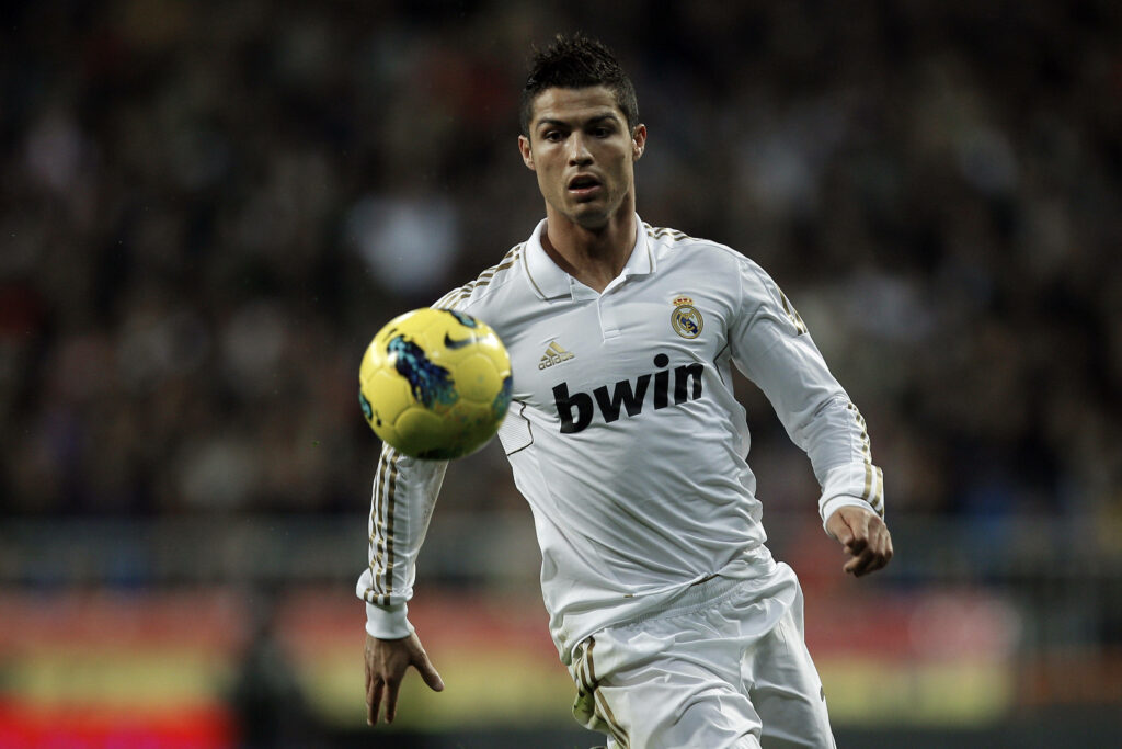 Cr7 in Pursuit: The Yellow Ball Chase - A Dynamic Background Photo of Cristiano Ronaldo Wallpaper
