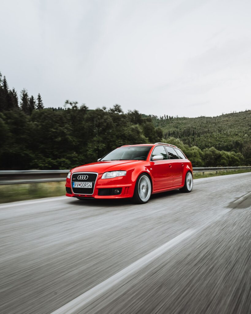 Dynamic Red Audi A4 Allroad Quattro in Motion with Lush Greenery Wallpaper