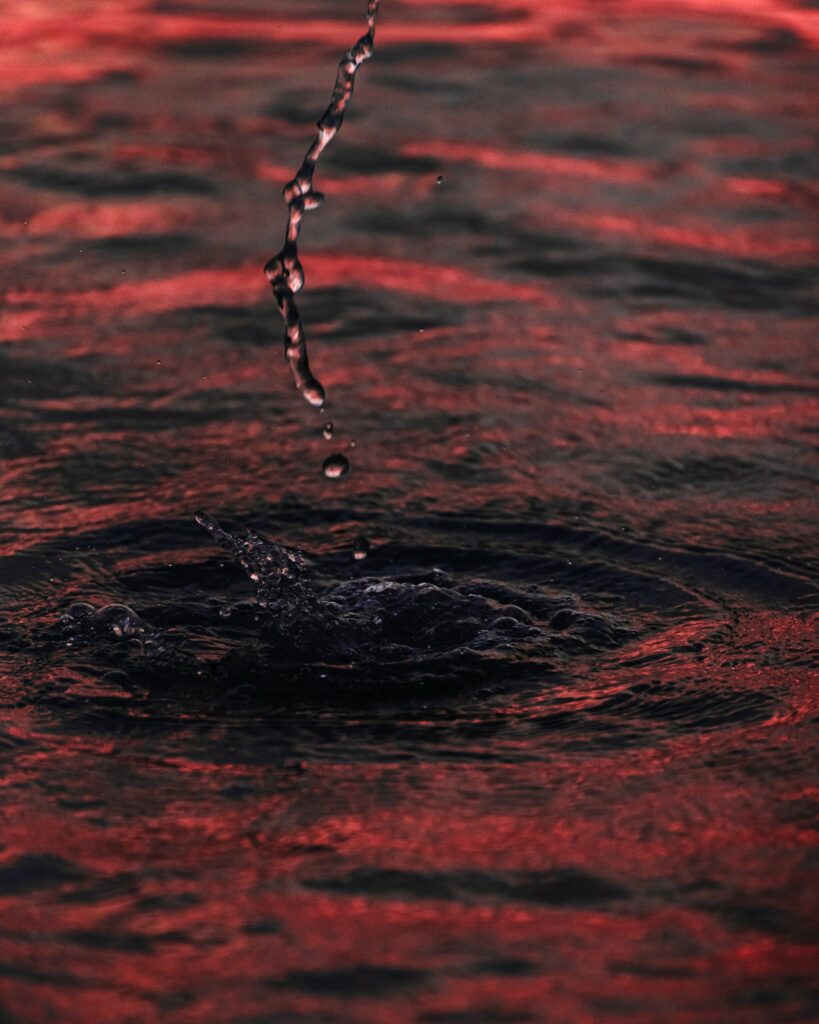 Abstract red and black water splash with droplets and rippling waves dynamic wallpaper background