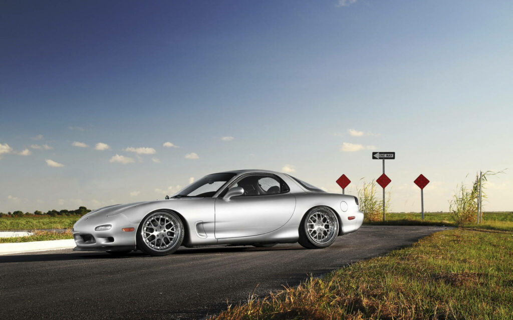 The Striking Silver Mazda Rx-7 Embraces Nature's Edges: A Captivating Rx7 Background Shot Wallpaper