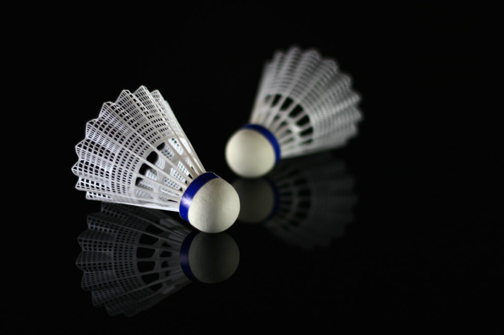 Exploring the Sport of Badminton: 4K Wallpaper featuring Twin White Shuttlecocks on Black Surface