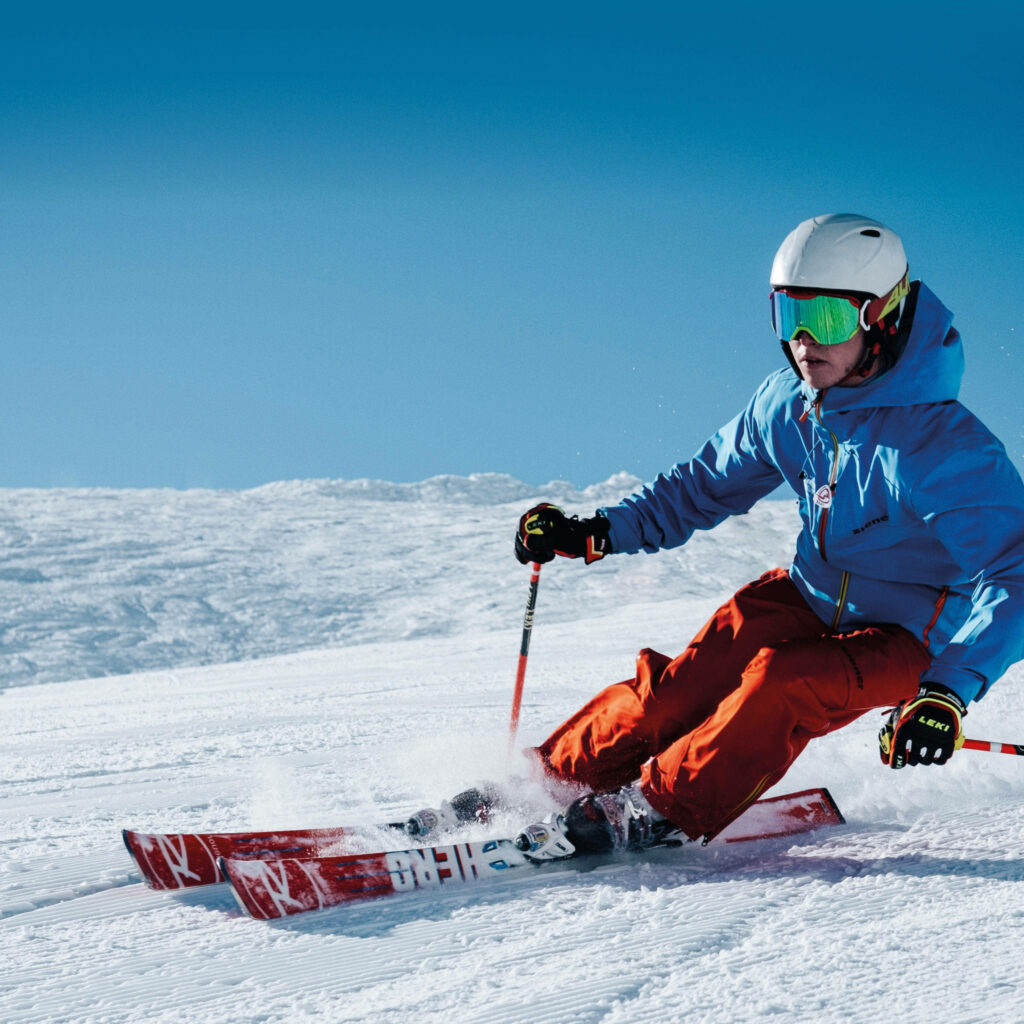 Thrilling Alpine Skiing Wallpaper: Skier on Pristine Snowy Slope
