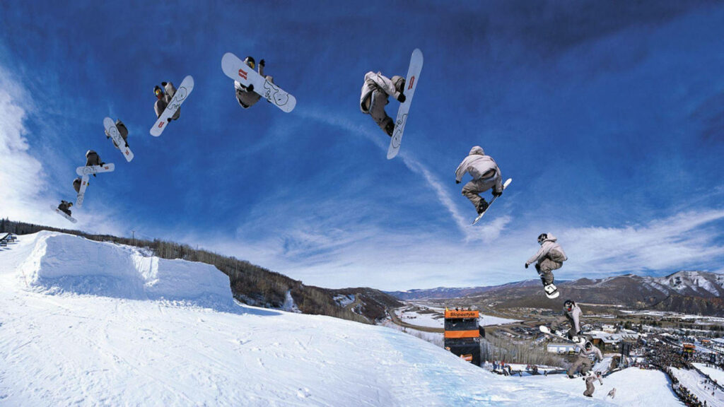 Dynamic Snowboard Jump Wallpaper Against Scenic Mountain Backdrop