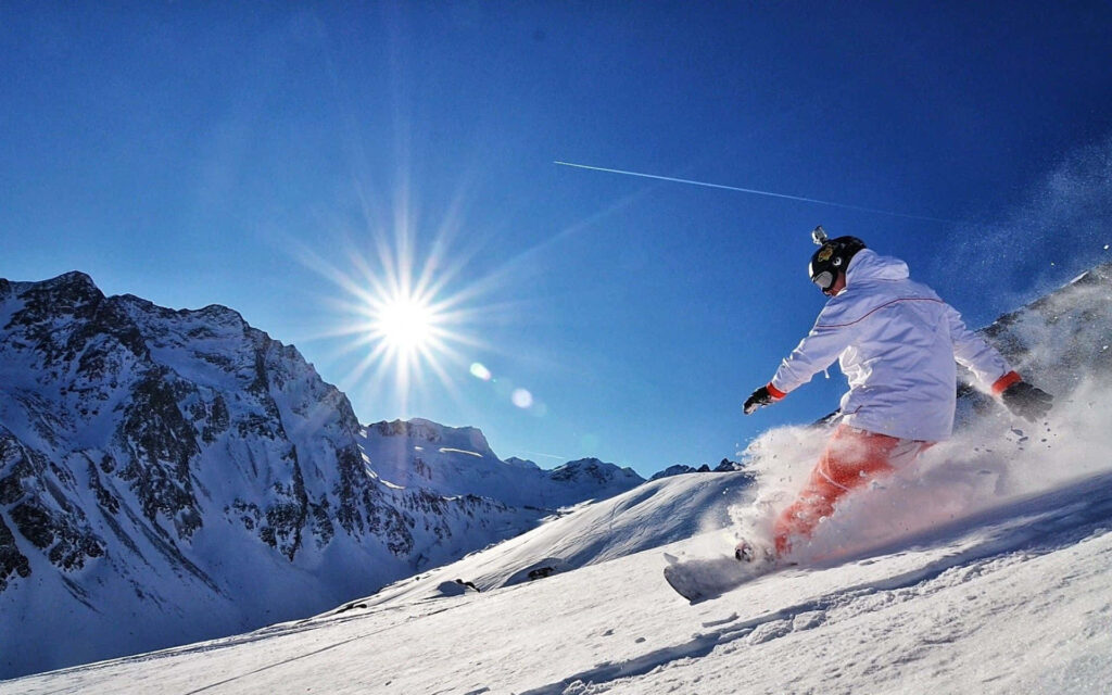 Dynamic Snowboarder Wallpaper: Bright Sky & Snowy Peaks