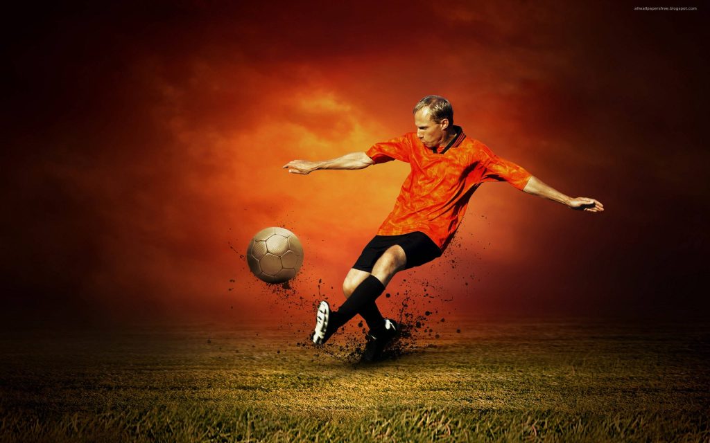 Soccer player striking ball with flying dirt against fiery orange sunset sky wallpaper background