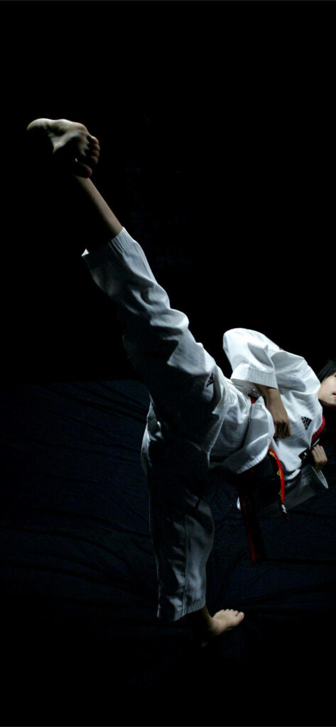 Dynamic Taekwondo Wallpaper: Powerful High Kick on Dark Background
