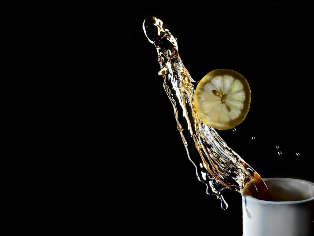 Fresh Tea Splash Wallpaper: Lemon Slice on Black Background