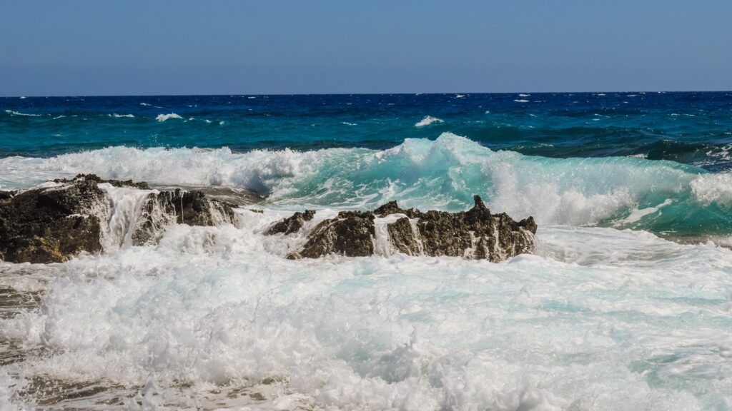 Powerful ocean waves crashing on rugged rocks vivid turquoise sea white foam natural energy wallpaper