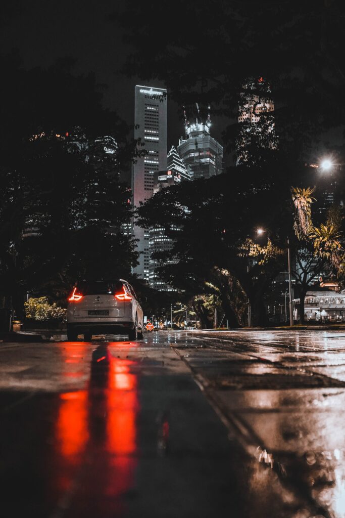 Sleek Car Wallpaper: Night City Lights & Wet Street Reflections