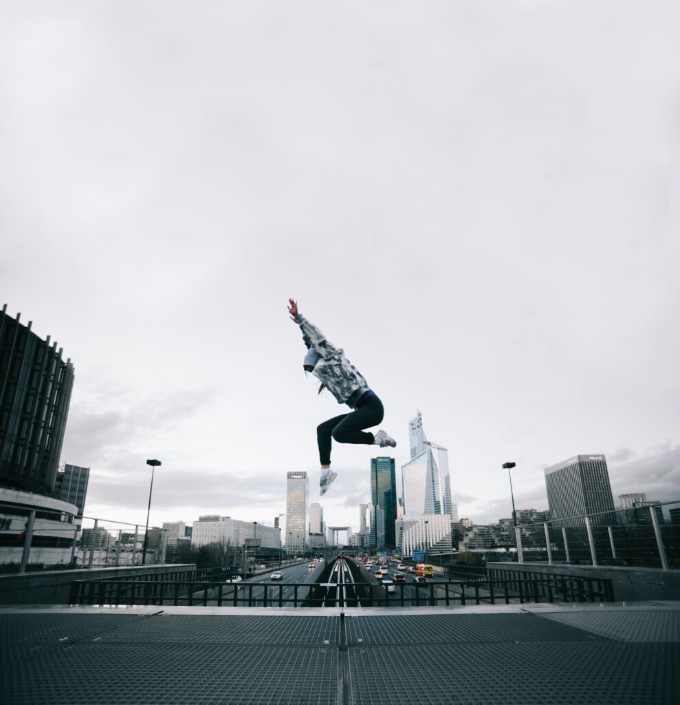 Dynamic Urban Wallpaper: Human Leap Against Skyline Backdrop