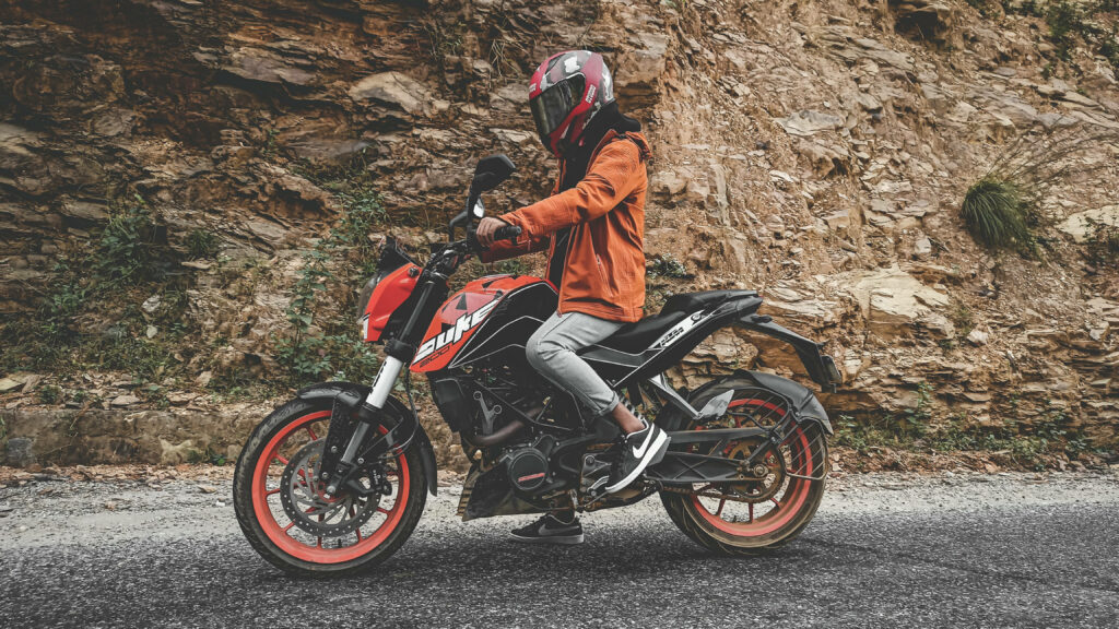 Adventure Wallpaper: Man on KTM Duke 200 Against Rugged Rocks