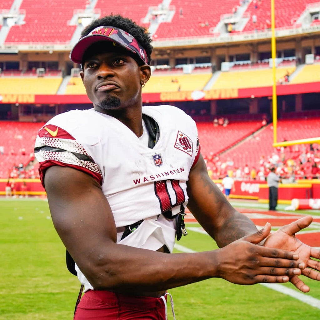 Brian Robinson Jr in Washington uniform warming up on field vibrant red stadium background wallpaper