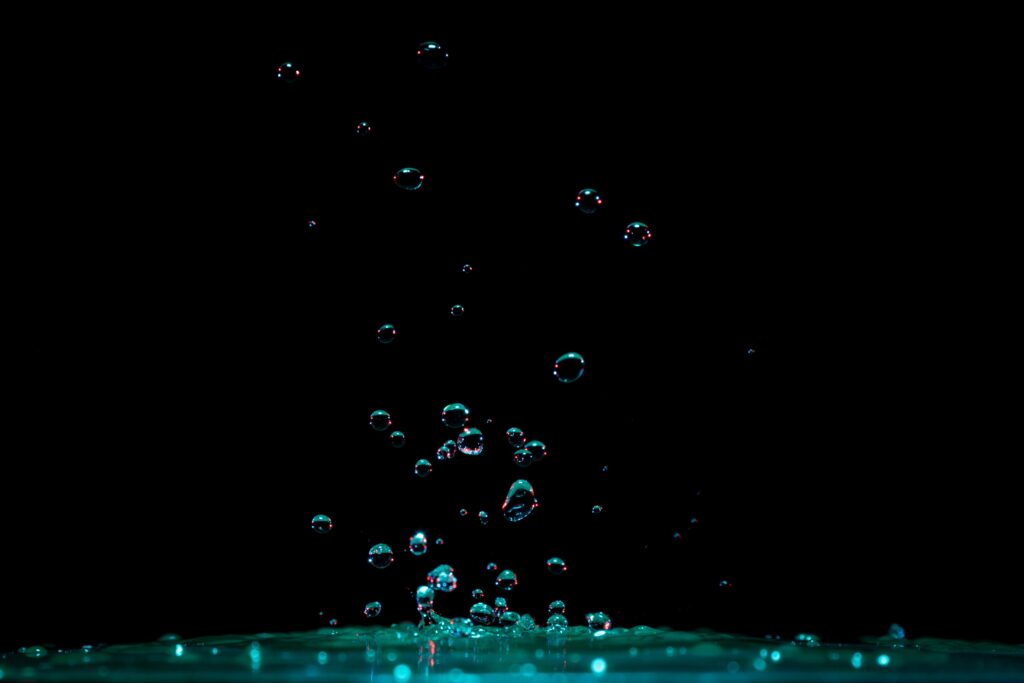 Captivating Water Droplet Wallpaper: Shimmering Splash on Dark Background