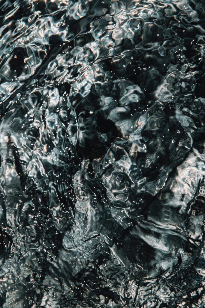 Abstract wallpaper with dynamic water ripples and shimmering reflections on dark surface