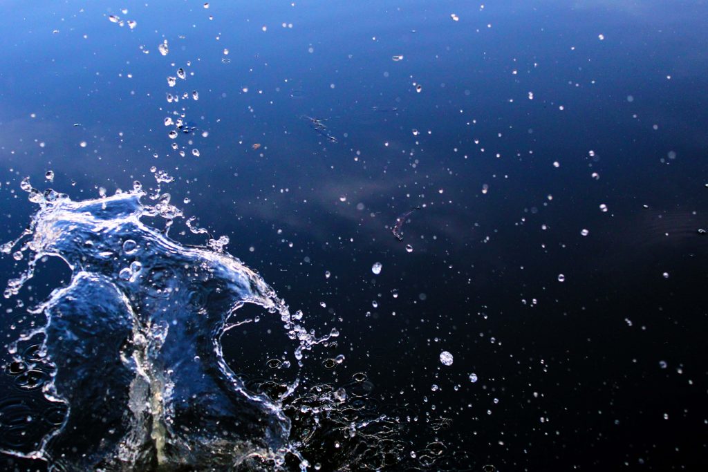 High-speed water splash with bright droplets on dark blue background vibrant wallpaper