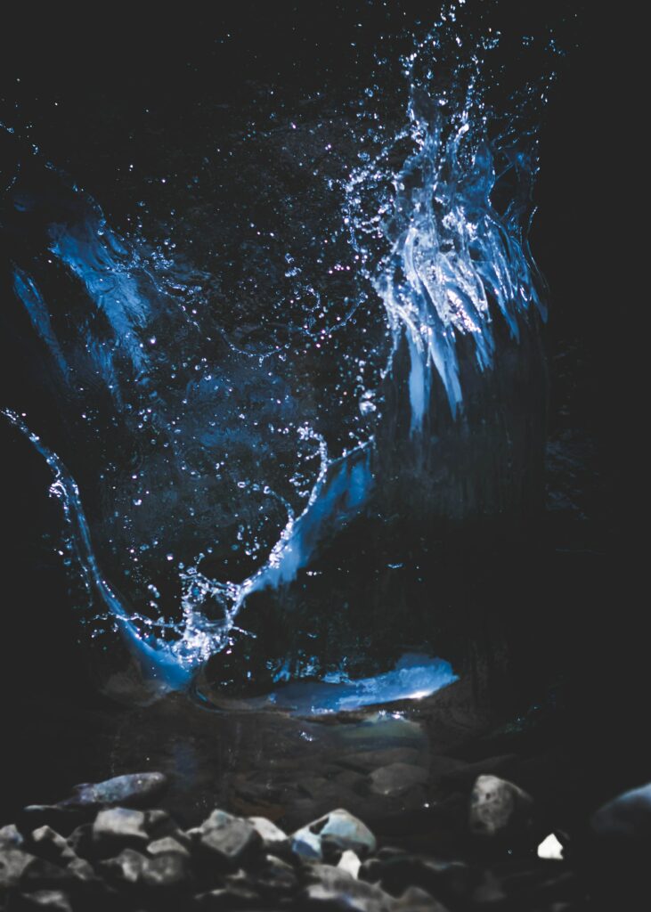 Dynamic Water Splash Wallpaper with Stones on Dark Background
