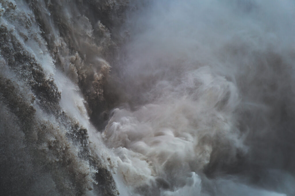 Powerful waterfall with swirling water and misty white and gray spray in high resolution wallpaper