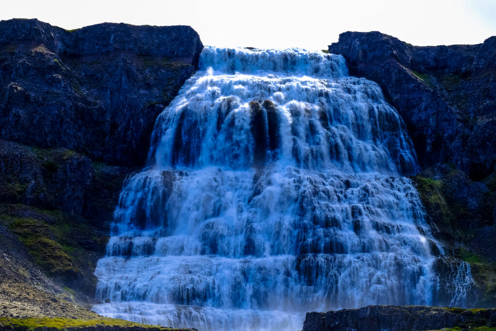 Powerful waterfall cascading over rugged rocks with deep blue water in a natural landscape wallpaper