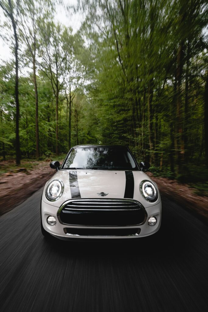 Dynamic White Mini Cooper in Motion on Forested Road Wallpaper