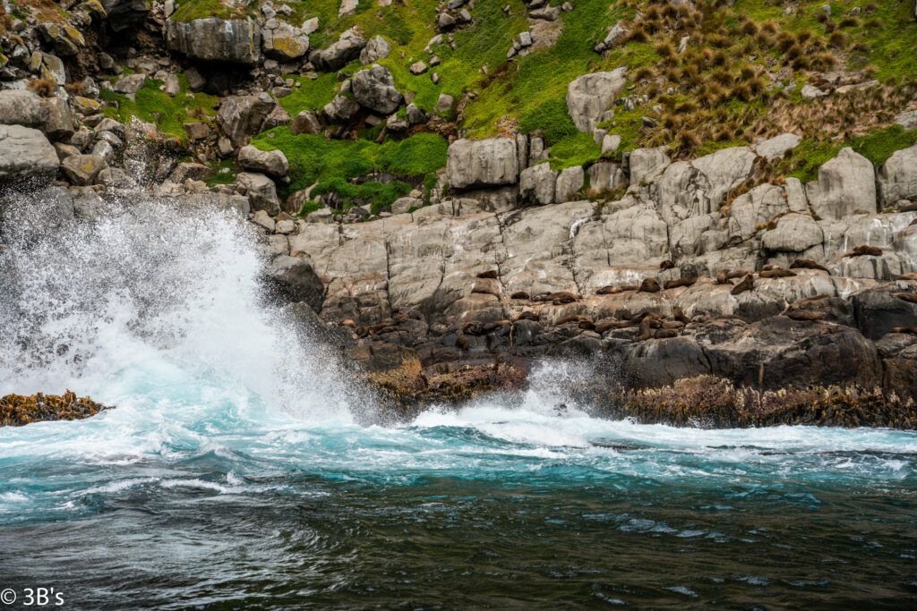 Dynamic river with white water crashing on rocks below green grassy rocky cliff wallpaper background