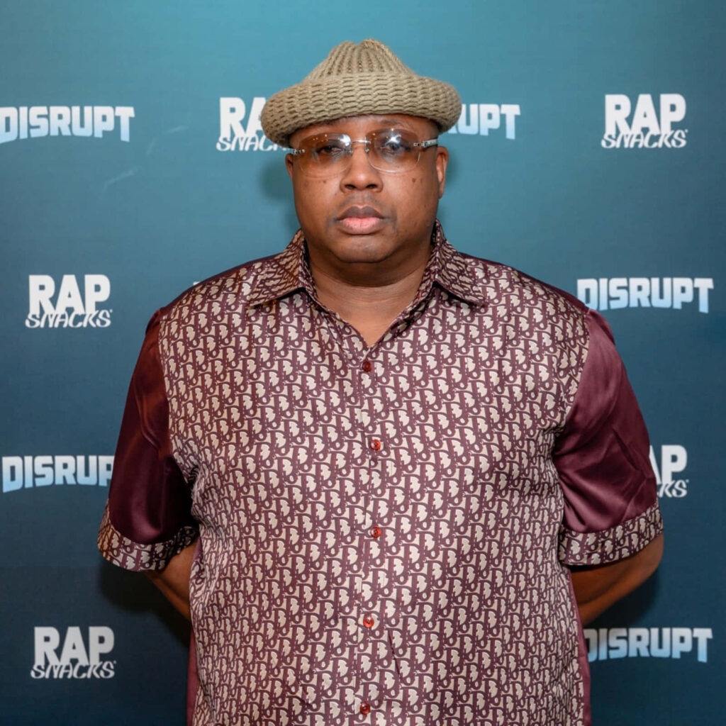 E-40 portrait at Rap Snacks event teal backdrop wearing patterned shirt and ribbed knit cap Wallpaper