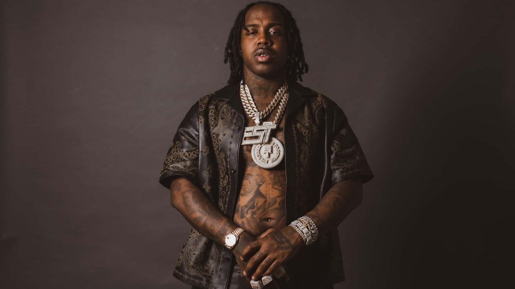 Portrait of rapper EST Gee with dreadlocks tattoos and diamond jewelry in moody studio lighting Wallpaper