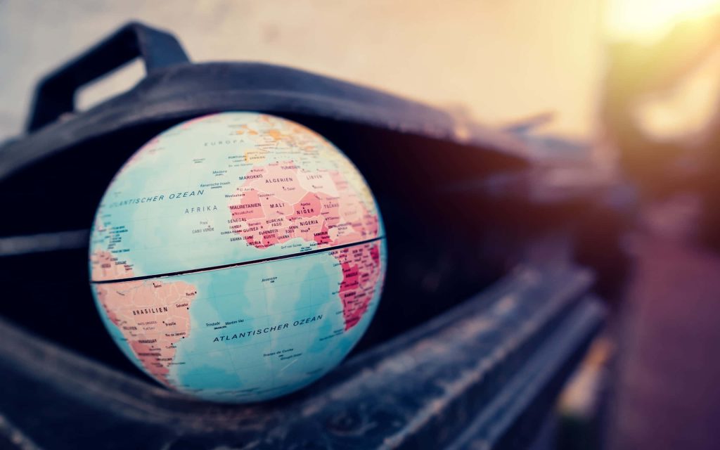 World globe discarded in black trash bin symbolizing environmental neglect at golden hour Wallpaper