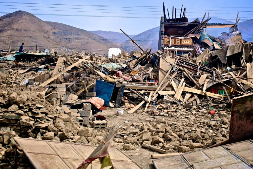 Earthquake aftermath with collapsed buildings debris and rugged hills in brown tones wallpaper background