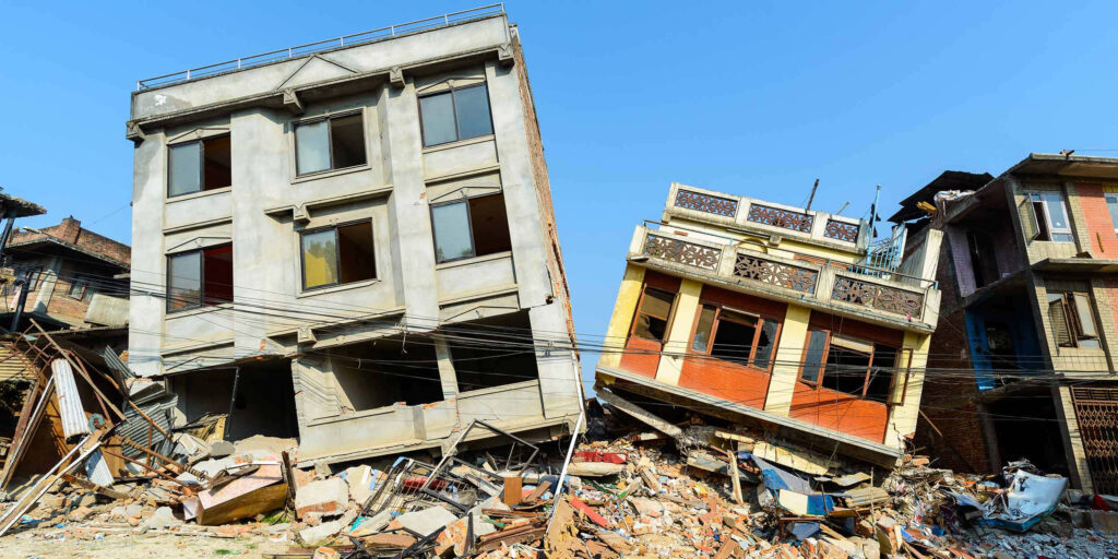 Earthquake aftermath wallpaper showing leaning buildings rubble and damaged power lines under blue sky