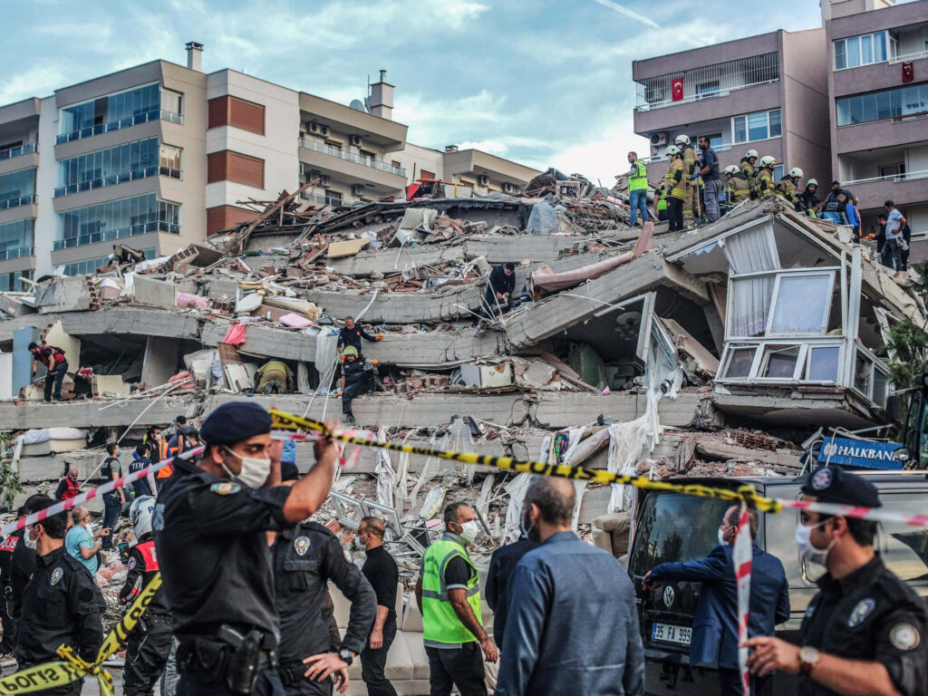 Earthquake aftermath with rescuers and civilians amid collapsed buildings and rubble urban disaster Wallpaper
