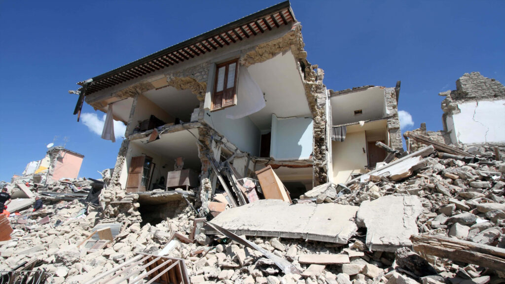 Earthquake damage wallpaper showing partially collapsed building rubble clear blue sky disaster
