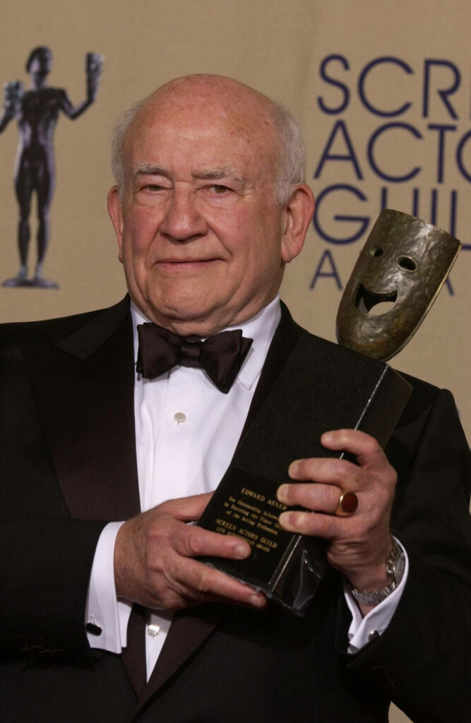 Ed Asner in tuxedo holding Screen Actors Guild Award trophy at SAG Awards with warm lighting Wallpaper