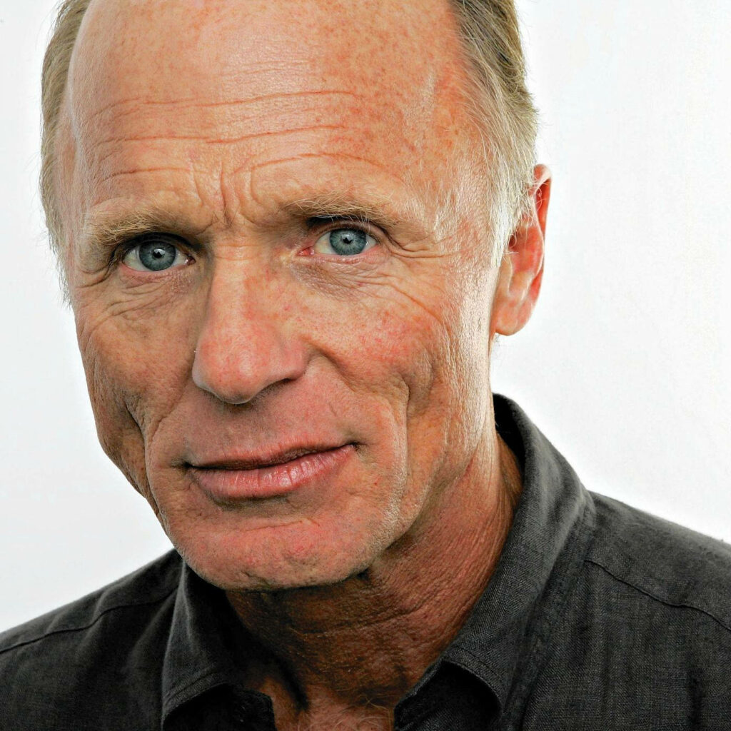 Close-up portrait of actor Ed Harris with intense blue eyes and textured skin wallpaper background