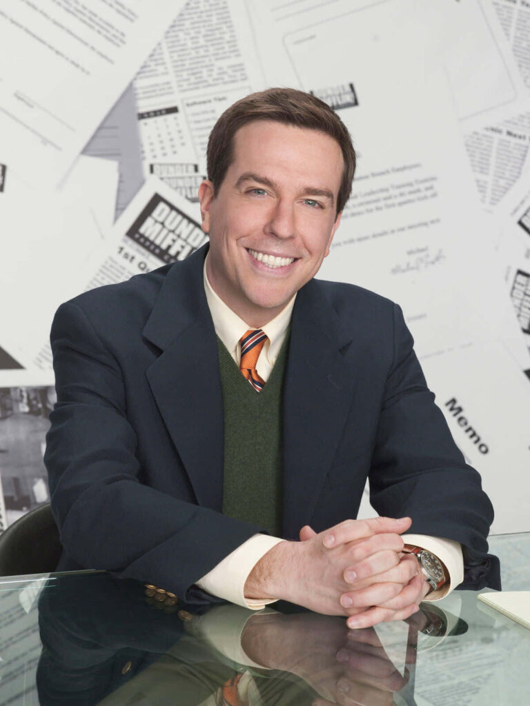 Comedic actor Ed Helms smiling in a casual interview with papers and documents background Wallpaper