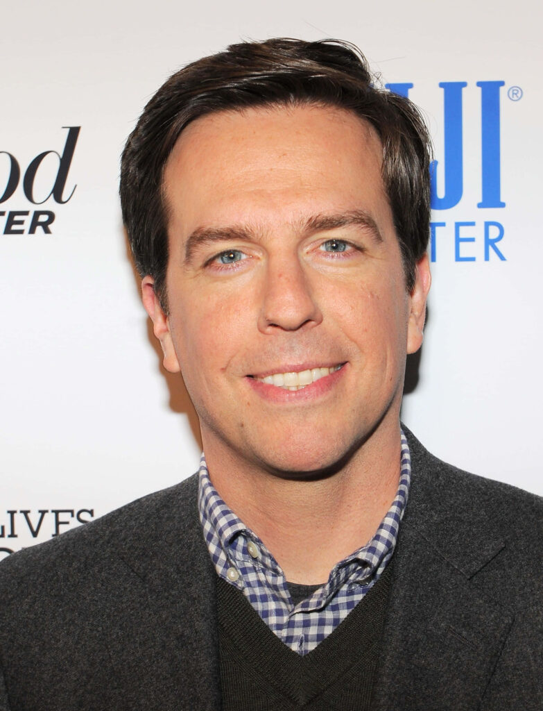 Ed Helms portrait wallpaper in checked shirt and blazer with light background and subtle branding