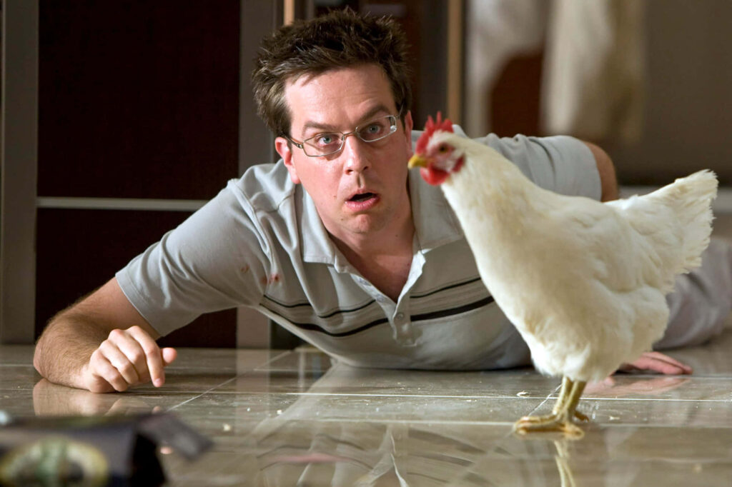 Ed Helms surprised on shiny tiled floor with white chicken bright playful comedy scene wallpaper