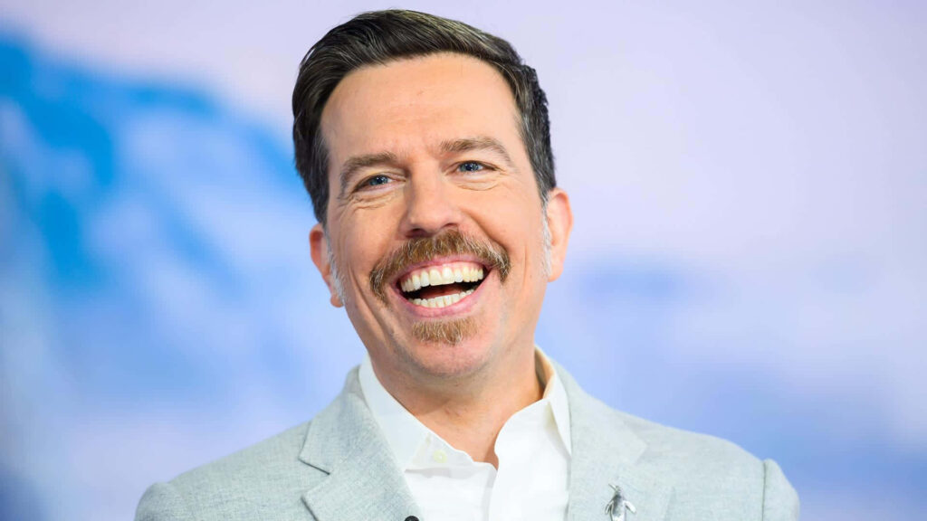 Ed Helms smiling in light gray suit against soft blue white background high resolution wallpaper