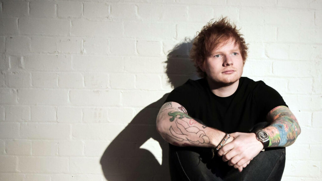 Ed Sheeran Wallpaper: Stylish Casual Look Against White Brick Wall