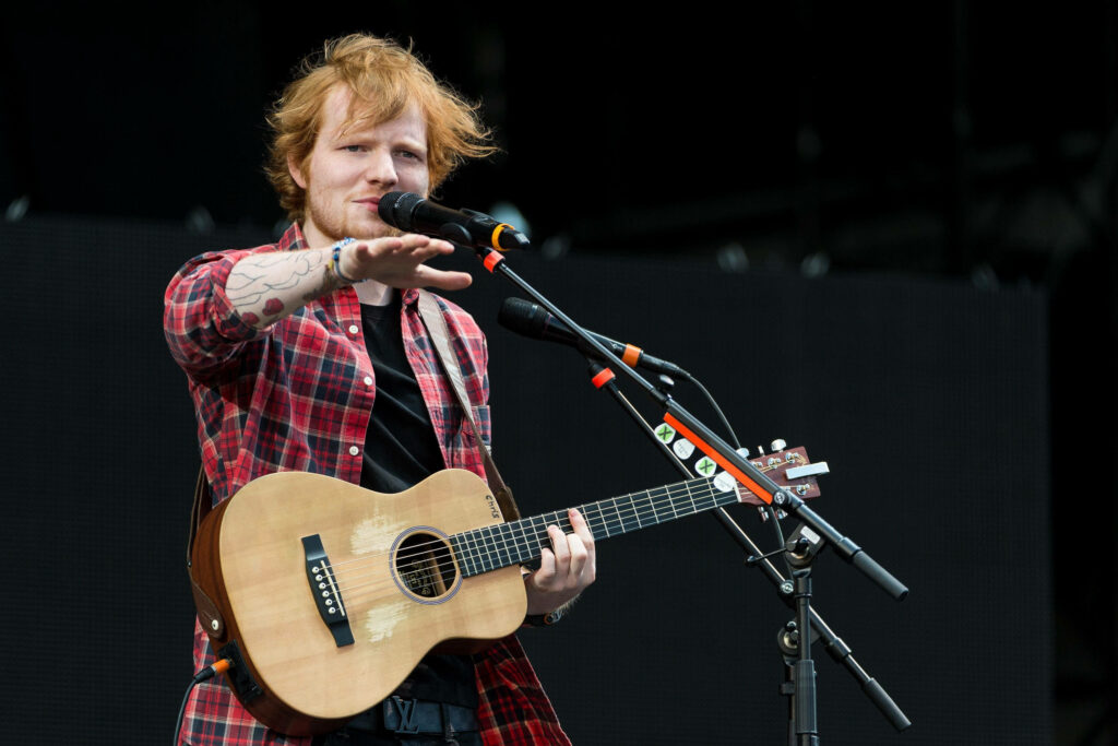 Ed Sheeran in Red Flannel: Lively Stage Performance Wallpaper