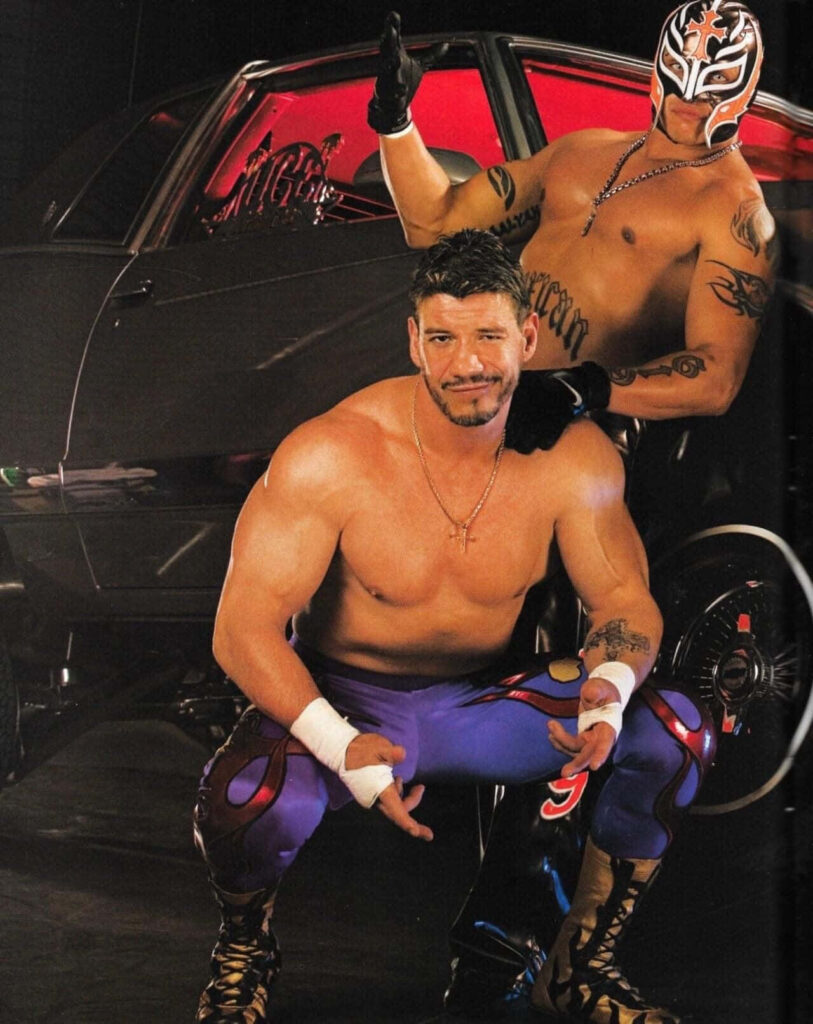Eddie Guerrero and Rey Mysterio in wrestling gear pose by stylish car vibrant WWE legends wallpaper background